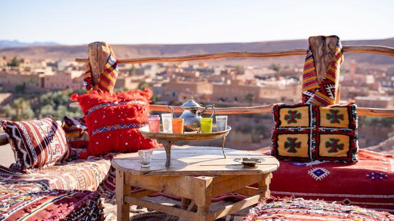Kettle with drinking glasses in tray on wooden table at rooftop restaurant against clear sky